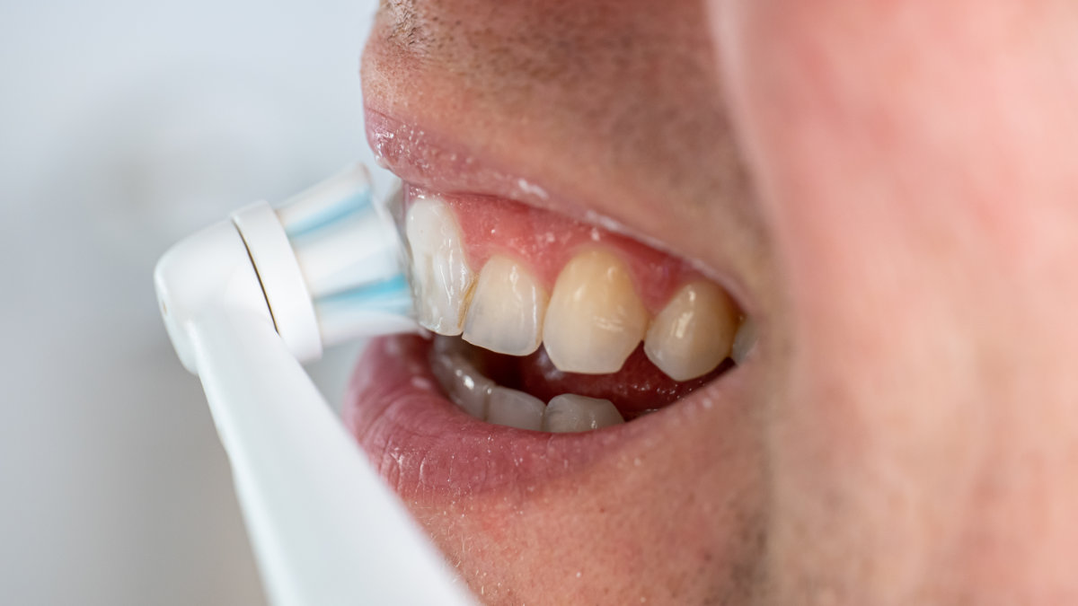 Person brushing teeth with electric toothbrush