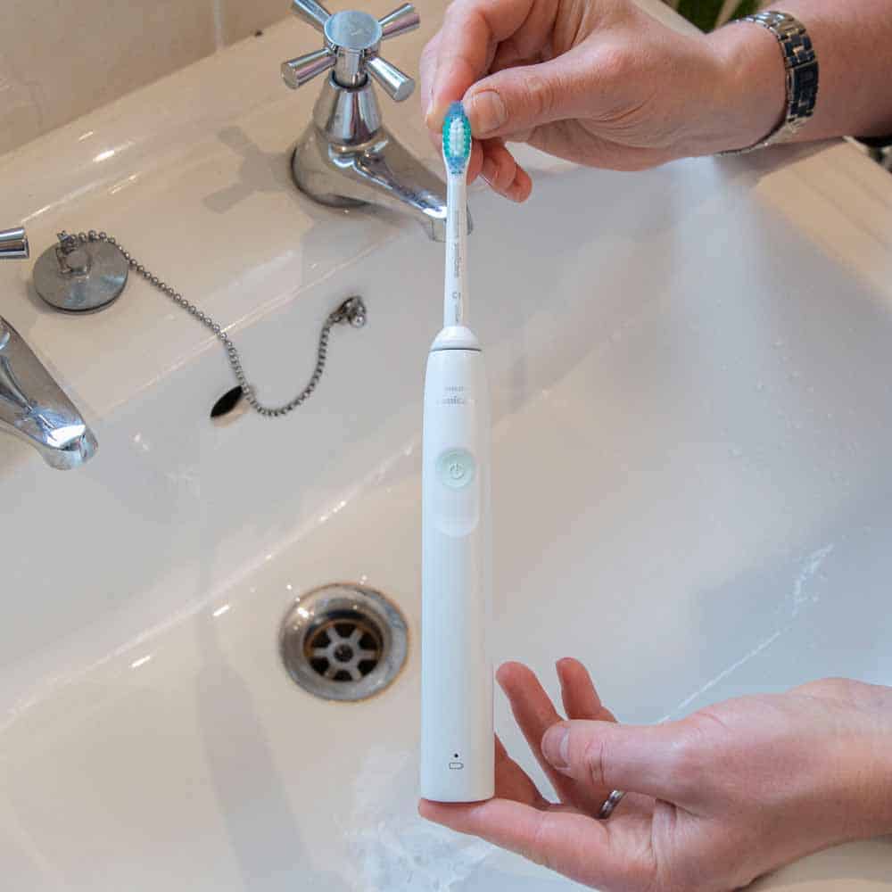 Sonicare 2100 Series heald between 2 hands above a sink