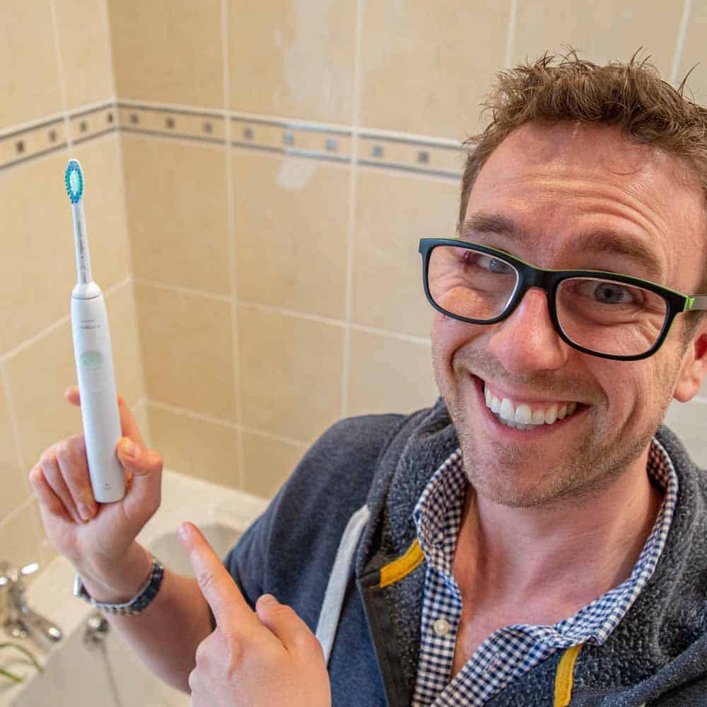 Man holding and pointing to the 2100 Series electric toothbrush