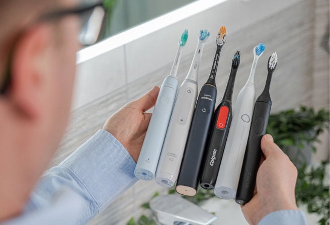 Jon holding various toothbrushes between two hands